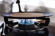 Close up shot of a kitchen stove with a frying pan and an undercook chapati (roti) on it