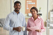 © Seventyfour - Waist up portrait of young black couple standing in office and looking at camera together