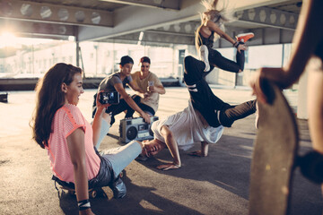 Wall Mural - Group of young people break dancing in a parking lot and recording with their smart phone