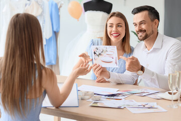 Wall Mural - Young couple with pictures planning their wedding in office