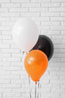 © Pixel-Shot - Different Halloween balloons near light brick wall in room