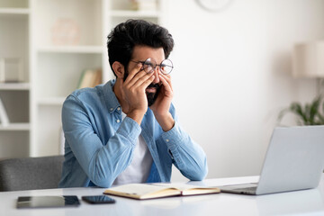 Glaucoma Concept. Young Indian Man Massaging Tired Eyes After Working On Laptop