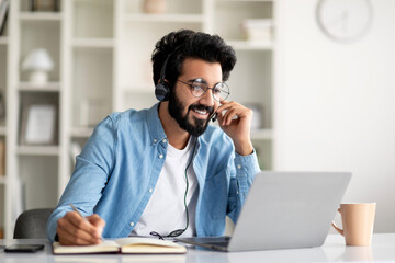Online Education. Indian Smiling Man In Headset Study With Laptop At Home