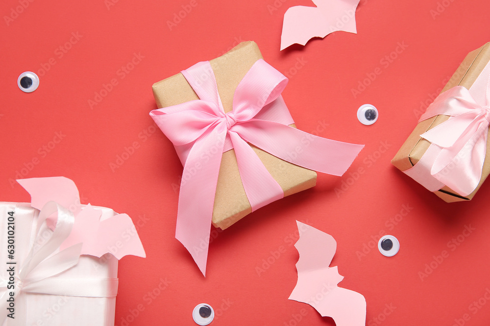 Composition with beautiful gift boxes and Halloween decor on red background, closeup