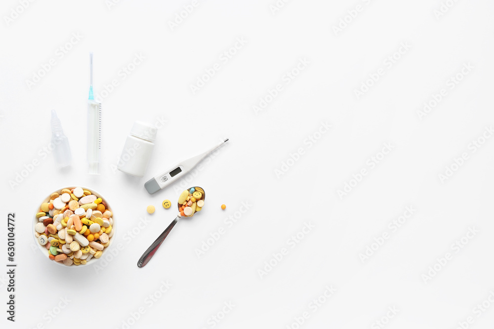 Pills, digital thermometer and syringe on white background