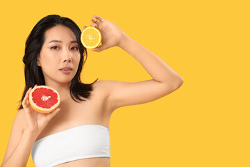 Sticker - Beautiful young Asian woman with citrus fruits on yellow background