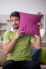 Wall Mural - Young man with a lot of pillows sitting on the sofa