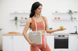 © sofiko14 - Slender caucasian woman with measuring tape and scales holding apple on palm while standing in kitchen. Effective health coach in sportswear assisting in weight management via healthy nutrition.