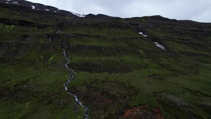 Wall Mural - DRONE AERIAL FOOTAGE: Road to Seydisfjordur, a colorful town in the east of Iceland. Waterfalls on the eastern Icelandic fjord during summer.