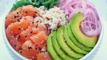 Poster - Poke bowl with salmon, rice, avocado, wakame salad, onion, circling on table. Healthy food, Asian raw meal. traditional Hawaiian raw fish salad. Japanese food.