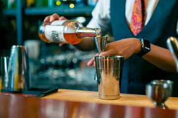 Poster - Professional Asian man bartender preparing and serving cocktail drink to customer on bar counter at nightclub. Barman making mixed alcoholic drink for celebrating holiday party at restaurant bar.