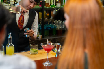 Poster - Professional Asian man bartender preparing and serving cocktail drink to customer on bar counter at nightclub. Barman making mixed alcoholic drink for celebrating holiday party at restaurant bar.