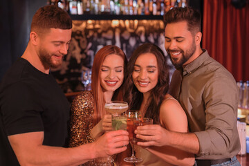 Sticker - Happy friends clinking glasses with fresh cocktails in bar