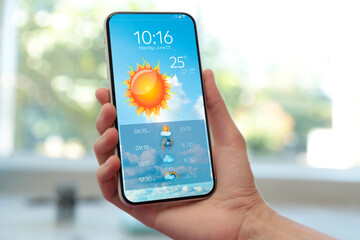 Wall Mural - woman checking weather using app on smartphone indoors, closeup. data, sun and other illustrations o