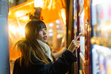 Happy Asian Woman Choosing And Buying Drinks On Snack And Beverage Vending Machine While Shopping At Shibuya, Tokyo, Japan. Attractive Girl Enjoy And Fun Outdoor Travel City Street On Autumn Vacation.
