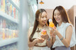 © twinsterphoto - Two beautiful Asian women shopping and checking items in supermarket. Female friends meeting and examining nutrition labels at convenient store