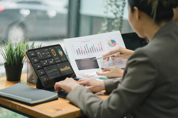 Two businesspeople or an accountant team are analyzing data charts, graphs, and a dashboard on a laptop screen in order to prepare a statistical report and discuss financial data in an office.