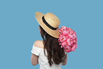 Poster - Beautiful young woman in straw hat with bouquet of pink peonies against light blue background