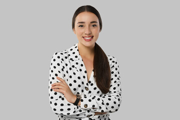 Poster - Portrait of beautiful young woman in polka dot blouse on light grey background