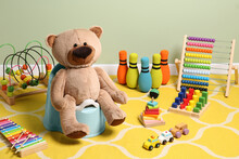 Teddy Bear On Light Blue Baby Potty And Many Other Toys Indoors. Toilet Training
