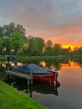 Fototapeta Pomosty - Scenic view of pond with moored boat at sunset