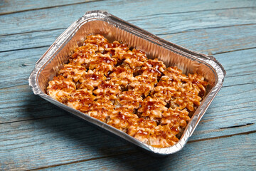 Baked sushi rolls in a baking dish on blue wooden background. Hot sushi rolls with different kind of fish and fillings. Exquisite baked sushi rolls