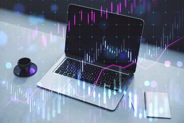 Poster - Close up of laptop at workplace with coffee cup, supplies and glowing candlestick forex chart on blurry background. Technology, trade and financial data concept. Double exposure.