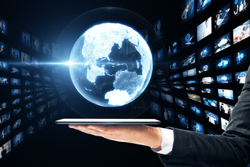 Poster - Close up of businessman hands holding tablet with creative glowing polygonal globe with rows of images on dark background. Connecting businesspeople, video conference concept.
