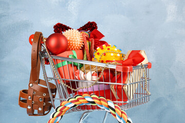Wall Mural - Small shopping cart with different pet goods and Christmas gifts on light blue background. Shop assortment