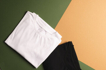 Close up of folded white and black t shirts and copy space on green to orange background