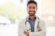 Portrait, smile and asian man doctor with arms crossed in hospital with stethoscope for consulting on blurred background. Happy, face and male healthcare expert proud of clinic, service or help