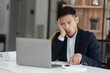 © SOMKID - sad asian businessman sitting at desk in modern office, stressed man, problem, Worried young man businessman,