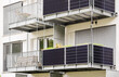 © Maryana - Solar Panels Balcony Apartment Building. Modern Balcony with Mini Solar Panel Installation in Green City. Solar Energy in Modern Facade Exterior Building