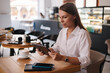 Side view of female freelancer working in cafe using digital tablet. Young business manager drink coffee during work break