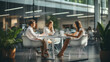 © annebel146 - Diverse millennial business team talking in meeting room, negotiating on project at table at glass wall panoramic window, discussing deal in open space, modern office interior. blurred background