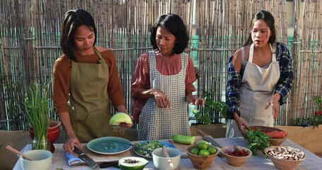 Wall Mural - Asian mother and adult daughters cooking thai dinner together while preparing papaya salad with fresh spicy dressing at home patio outdoor 