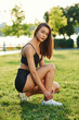 © standret - Ties shoelaces. Beautiful young woman in sportive clothes is in the park at sunny daytime