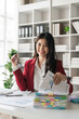 © Natee Meepian - Portrait of young attractive asian woman with relaxing while sitting at her office desk,open a large pile of documents smiling and looking at camera