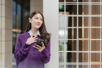 Beautiful successful asian businesswoman holding mobile phone using smartphone in office chatting with business mannequin 