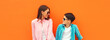 © rohappy - Stylish happy smiling mother with son teenager posing together in sunglasses, checkered shirts, jeans in the city on orange background