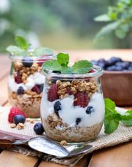 Wall Mural - Yogurt parfait with granola, blueberries and raspberries garnished with mint