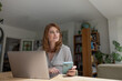 © ReeldealHD images - Young adult female working on personal finances using a laptop and a smartphone