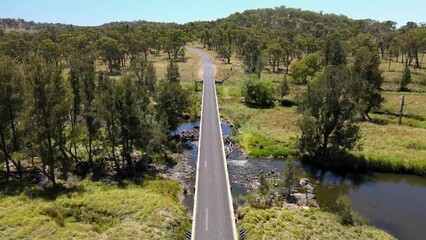 Sticker - Drone view of vehicles on a long bridge road on a river with plains and trees