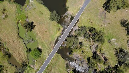 Canvas Print - High drone view of vehicles on a long bridge road on a river with plains and trees