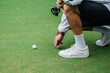 © Nadzeya - Golfer using pin marking position of golf ball on green