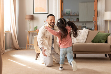 Wall Mural - Korean daughter running towards her dad to embrace him indoor