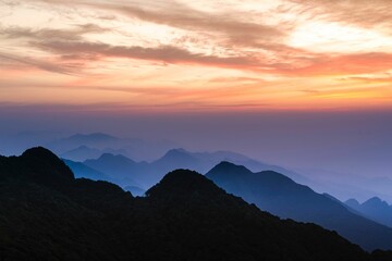 Poster - Stunning landscape of mountain ranges silhouetted against a vibrant sunrise