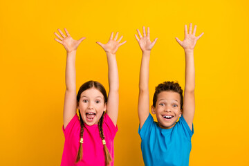 photo of cute excited preteen schoolchildren wear t-shirts screaming rising arms isolated yellow col