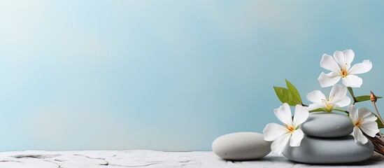 Poster - A tranquil spa and wellness concept with a pile of Zen stones, flowers, and towels placed on a light blue background with room for text. A calm and soothing treatment that promotes relaxation. A