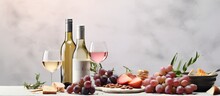 A bottle of pink wine with an appetizer set is featured in a romantic dinner scene on a light gray stone background. represents Mediterranean food and drinks for a wine party dinner.